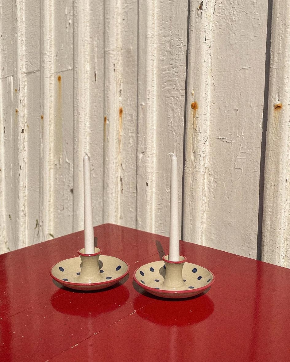 Handcrafted Spanish ceramic candle holders with blue polka dots, white candles on vibrant red surface