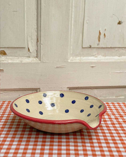 Handcrafted Spanish ceramic large egg plate with blue polka dots and red rim, displayed on orange gingham tablecloth