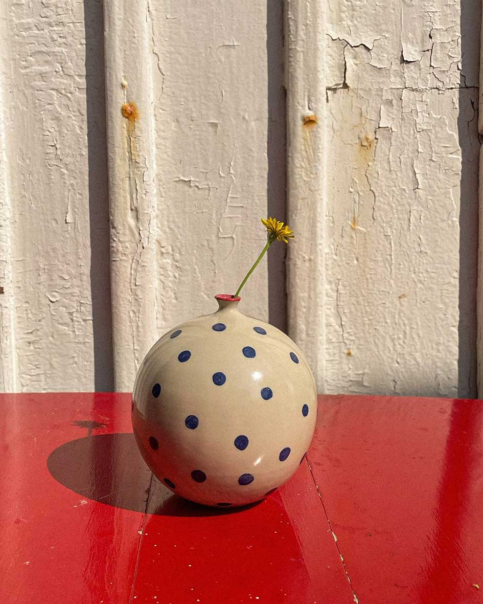 Handcrafted Spanish ceramic large vase with blue polka dots and red rim, featuring yellow wildflower on vibrant red surface