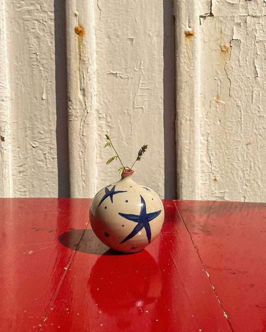 Handcrafted Spanish ceramic small vase with blue star design, featuring delicate botanical accent on vibrant red surface